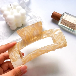 Close-up of large cream marbled acetate hair claw clip for elegant bun styling