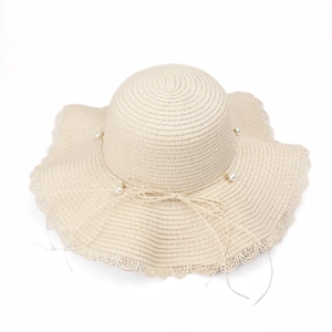 Close-up of elegant women's straw sun hat featuring pearl accents and a wavy wide brim