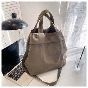 Deep khaki nylon tote bag on a desk next to a laptop in a bright office setting