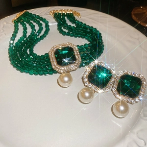 Macro view of multi-strand green bead choker with emerald-cut gem and pearl detail