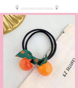 Detail of high-elasticity hair tie with orange resin beads and green polka dot bow decor