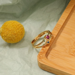 Detail view of a gold open ring with colorful red blue and green round cut gemstones