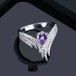 Détail macro d'une bague de luxe en argent avec zircon violet poire et anneau en forme d'aile