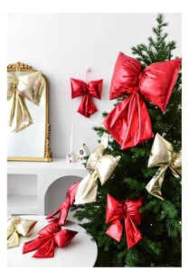 Large metallic red and gold Christmas bows displayed on a festive tree and table decor