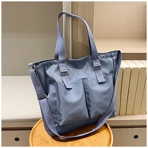 Detail of blue nylon tote bag with dual front pockets and adjustable crossbody strap