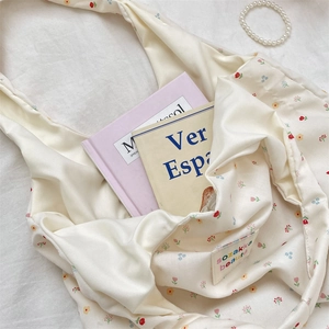 Macro view of the cream floral fabric texture and sewn label on the soft tote bag