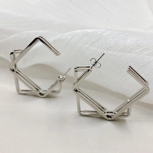 Elegant geometric square silver earrings for women on a white satin fabric background