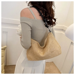 Dettaglio di una borsa tote in paglia color malto con spalline in pelle nera