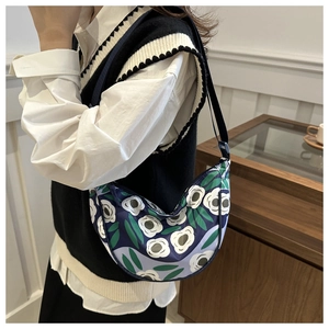 Blue crossbody moon bag featuring bold white floral pattern and adjustable shoulder strap