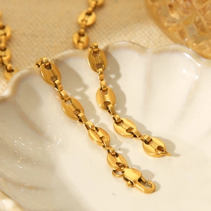 Close-up of golden pig nose link necklace chain resting in a white shell dish