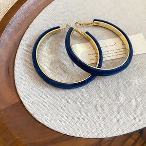 Detail of dark blue flocked geometric hoop earrings on a natural linen and wood background