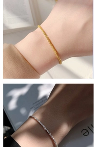 Detail shot of delicate shimmering gold and silver chains worn on wrists with natural lighting