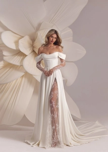 Detailed view of white off-shoulder wedding dress with lace sleeves and high slit skirt