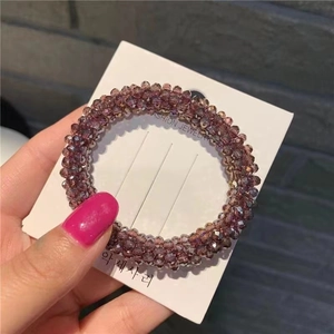 Detailed view of a purple beaded crystal hair tie on a white fashion jewelry display card