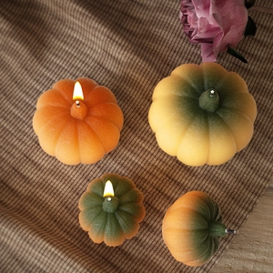 Realistic pumpkin candles in various colors on vintage fabric for festive decor