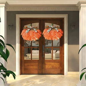 Symmetric pumpkin wreaths made of orange mesh fabric on wooden front porch doors