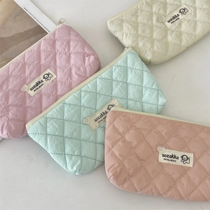 Close-up of quilted cosmetic bags with heart-shaped zipper and cute dog emblem