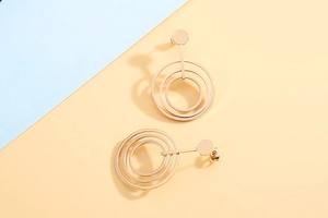 Detail of rose gold triple geometric hoop earrings with polished metal surface