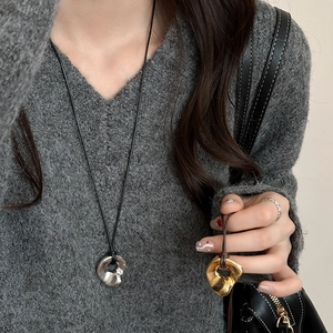 Minimalist irregular metal pendant necklace in gold and silver on a dark sweater