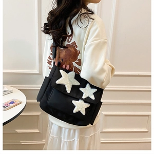 Detail of black crossbody messenger bag with three white plush star appliques