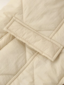 Detailed macro view of beige quilted diamond stitching and pocket on the jacket