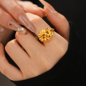 Detailed macro view of a 24k gold-plated flower cluster ring worn on the finger