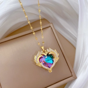 Macro detail of gold necklace featuring rainbow crystal heart and winged diamond accents