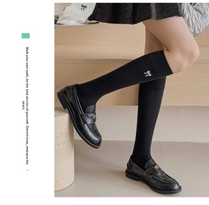 Detailed embroidery of white bows on black knee-high cotton socks in Japanese JK style