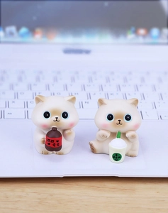 Close-up of cute resin cat figurines holding miniature drinks on a laptop keyboard
