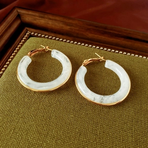 Detailed macro view of retro C-shaped resin hoop earrings with gold plating and marble texture