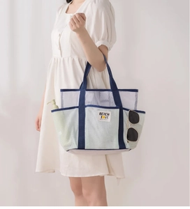 White mesh beach tote with navy blue straps and Beach Love label held by model
