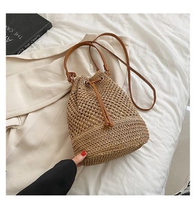 Detail of woven straw bucket bag texture with brown leather drawstring and strap