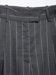 Close-up of waistline detail on dark grey pinstripe trousers showing button and belt loops