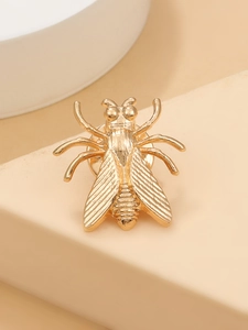 Detailed view of a golden insect cicada earring on a beige geometric display stand