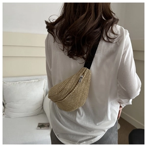 Detailed texture of woven straw chest bag with adjustable black strap on casual model