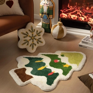 Close-up of a tufted Christmas tree shaped rug and decorative snowflake pillow by a fireplace