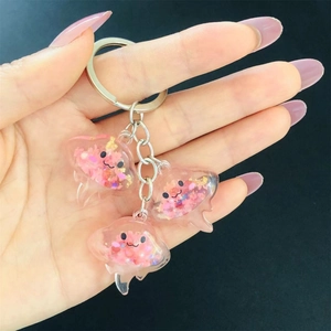 Detail of pink luminous resin jellyfish keychains with sequins on a dark background