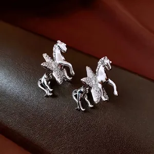 Polished silver Pegasus earrings with cubic zirconia wings on premium leather surface