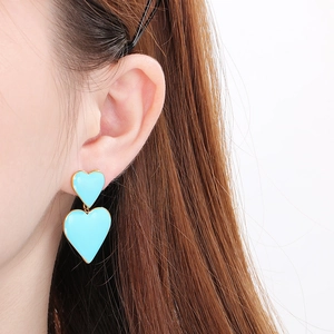 Détail de boucles d'oreilles cœur bleu clair superposées avec bordure plaquée or 18k