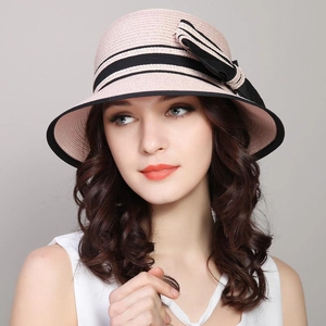 Pink woven sun straw hat with a black ribbon bow and wide brim for summer travel