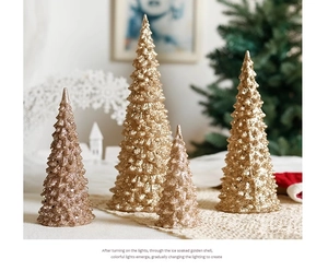 Close-up of sparkling gold acrylic Christmas trees with glitter finish on a lace tablecloth