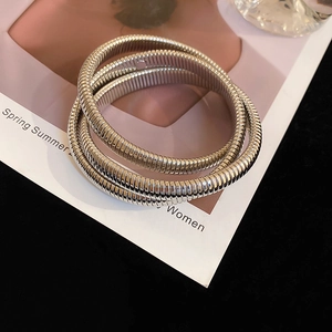 Close-up of silver triple-layered spiral bracelet with fine ribbed texture on magazine