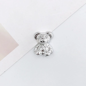 Macro shot of silver plated teddy bear charm showing metallic finish and smooth texture