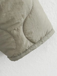 Macro detail of muted olive quilted jacket sleeve with wave stitching and refined texture