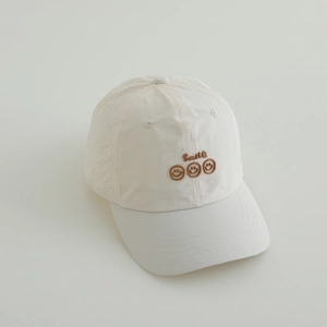 Close-up of white sun hat featuring brown Smile embroidery and side ventilation holes