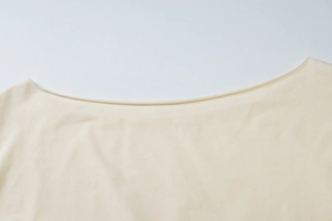 Detailed close-up of the elegant boat neck design on a soft beige knitted top