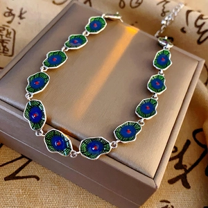 Close-up of silver-tone bracelet with blue and green enamel lotus-leaf-style charms