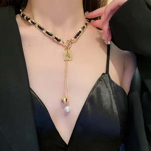 Detail of faux leather chain necklace with square letter pendant and pearl charm