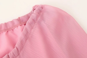 Détail d'une robe rose en mousseline à col en V avec des volants et des coutures précises