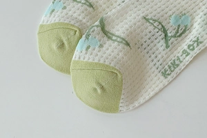 Close-up of light green mesh socks with fruit jacquard and KIKI SOX branding detail